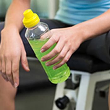 Person in workout clothes holding drink bottle with green liquid